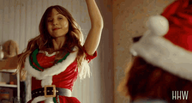 a woman in a santa costume is dancing in a room
