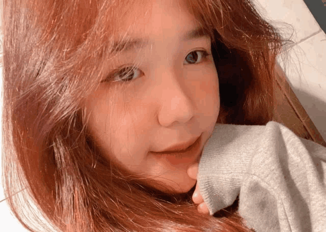 a close up of a woman 's face with a gray sweater on