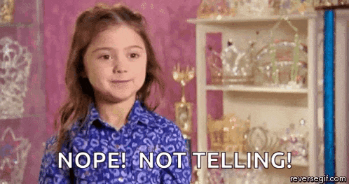 a little girl in a blue shirt is standing in front of a shelf and saying nope ! not telling !