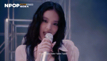a woman is singing into a microphone while wearing a pink dress .