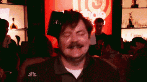 a man with a mustache is standing in front of a sign that says nbc on it .
