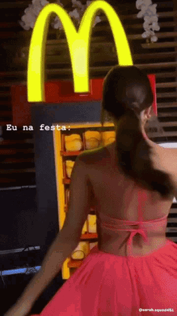 a woman in a pink dress is standing in front of a mcdonalds sign