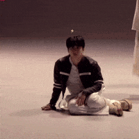 a man in a black jacket and white pants is kneeling down on the floor