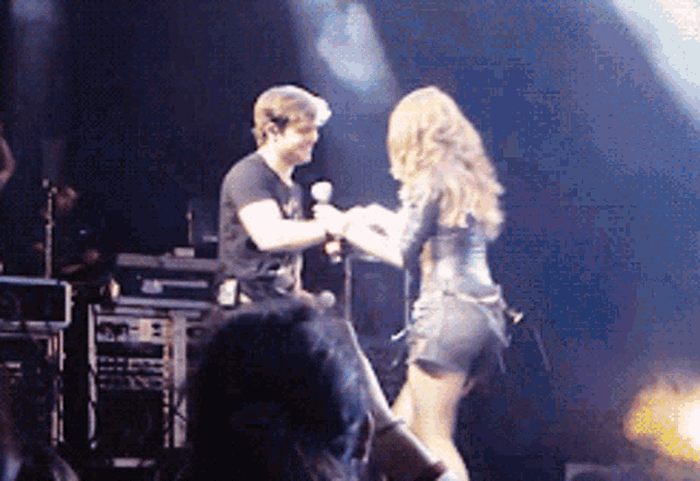 a man and a woman are holding hands on stage