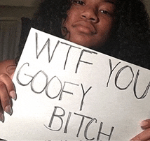 a woman holds a sign that says wtf you goofy bitch