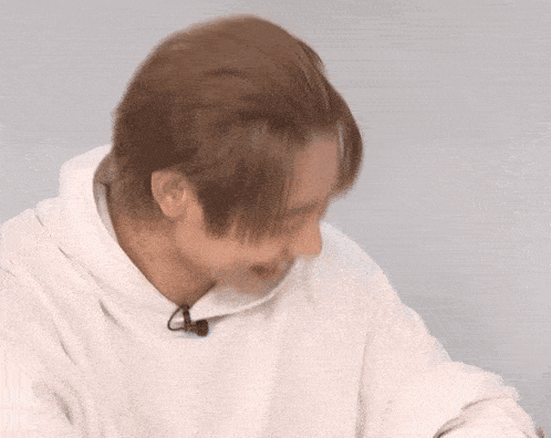 a man wearing a white hoodie has a microphone on his ear
