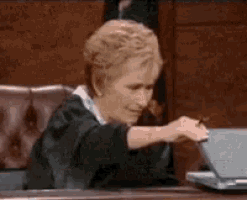 a woman in a judge 's robe is sitting at a desk using a laptop computer .