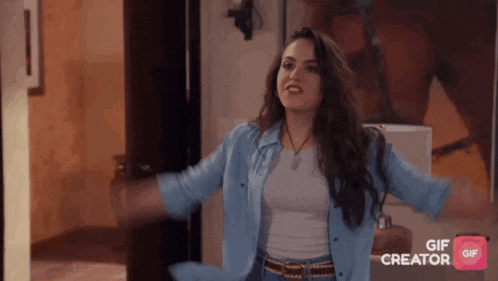 a woman in a blue shirt is standing with her arms outstretched in front of a gif creator button