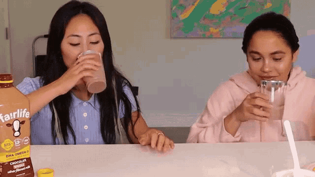 two women drinking from cups next to a bottle of starlife