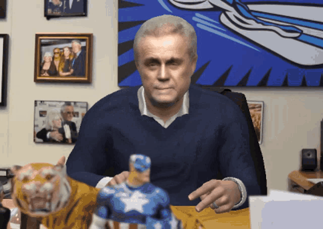 a man is sitting at a desk with a tiger and a captain america figurine