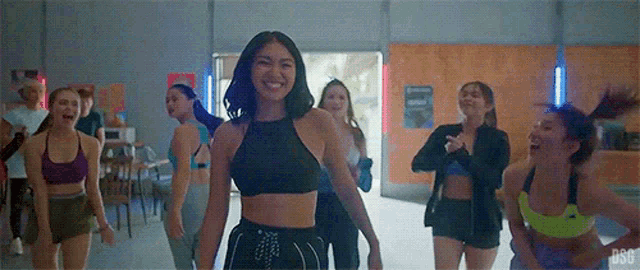 a group of young women are dancing together in a gym and smiling .