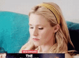a woman wearing a yellow headband is sitting on a couch holding a dvd of a new episode of the simpsons