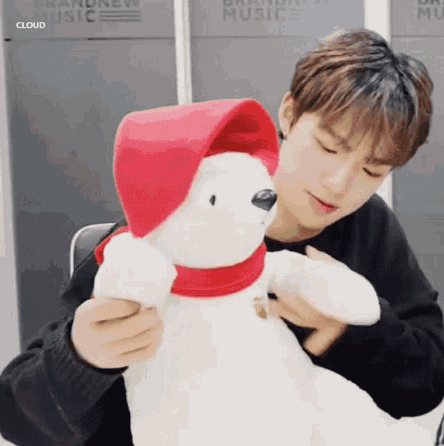 a young man is holding a stuffed polar bear wearing a red hat and scarf .