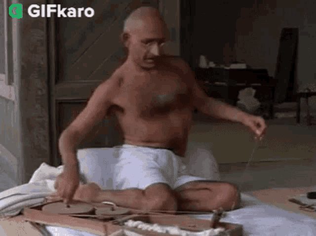 a shirtless man is sitting on a bed and playing a musical instrument .