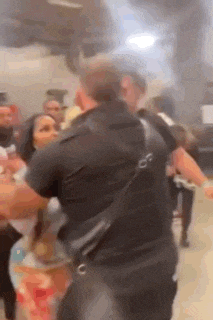 a man and woman are fighting in a crowded room .