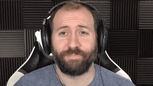 a man with a beard wearing headphones is sitting in a chair .