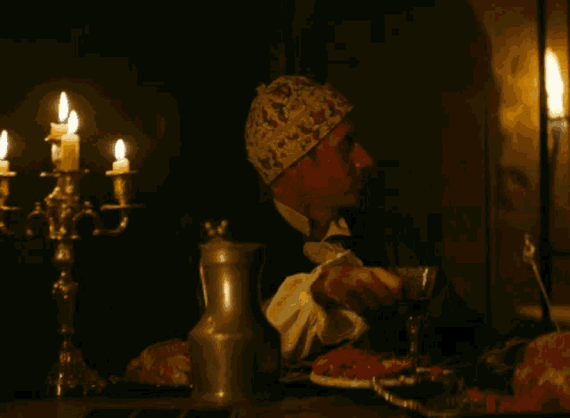 a man is sitting at a table with candles and a pitcher