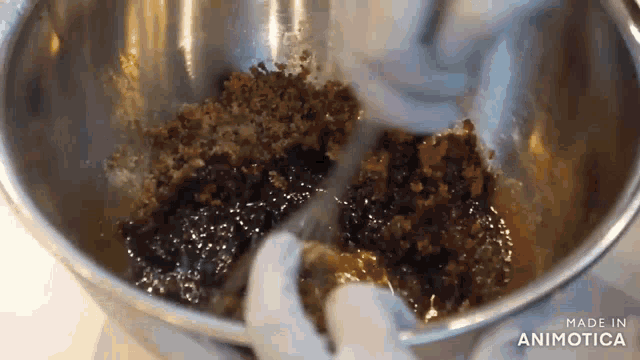 a person is mixing a mixture in a metal bowl .
