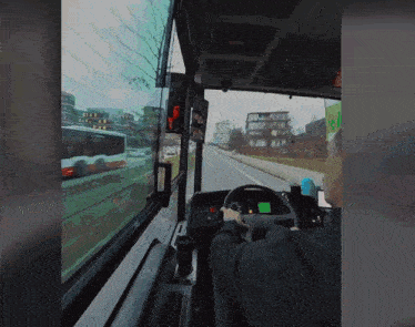 a man is driving a bus with a green screen on the steering wheel