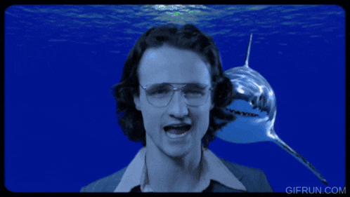 a man with glasses is standing in front of a shark with the words i would or r written on it