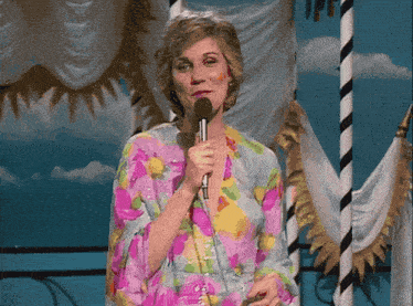 a woman in a floral dress holds a microphone