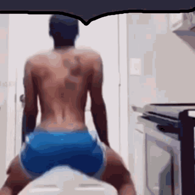 a shirtless man in blue shorts is sitting on a white toilet .