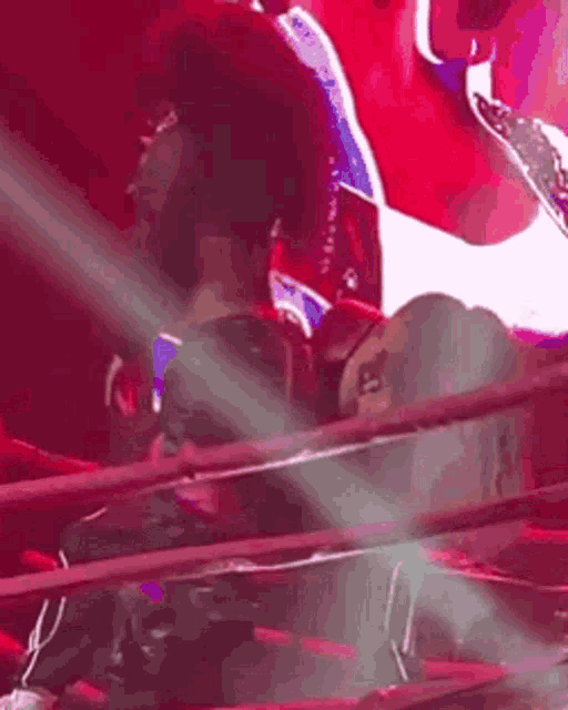 a man is sitting in a boxing ring with a red light coming out of the ring .