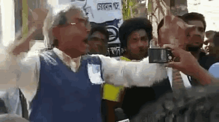a man in a blue vest is taking a picture of a crowd of people .