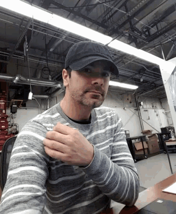 a man wearing a hat and a striped sweater is sitting at a desk