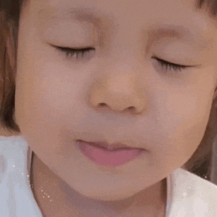 a close up of a little girl 's face with her eyes closed and her mouth open .