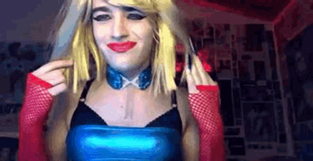 a woman in a blue top and red gloves is making a funny face while wearing a wig .