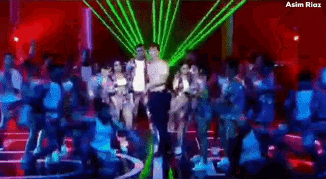 a group of people are dancing in a dark room with green lights coming out of the ceiling