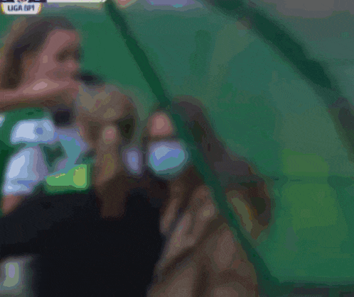 a female soccer player in a green jersey is being held by a referee