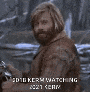 a man with a beard is looking at the camera with the words 2018 kern watching 2021 kern written below him .