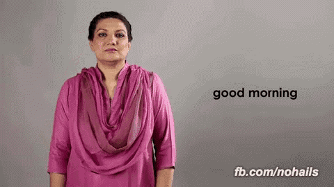 a woman in a pink shirt is making a gesture that says `` good morning '' .