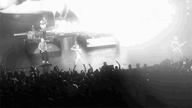 a black and white photo of a band performing on stage in front of a crowd