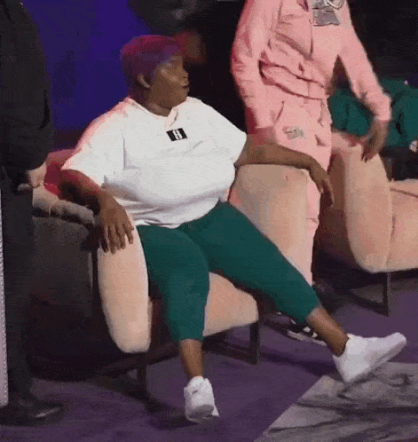 a woman in a white shirt is sitting in a chair with her legs crossed