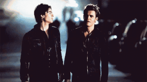 two men are standing next to each other holding hands in a dark street .