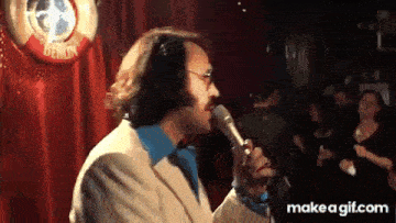 a man is singing into a microphone while wearing headphones and a suit .