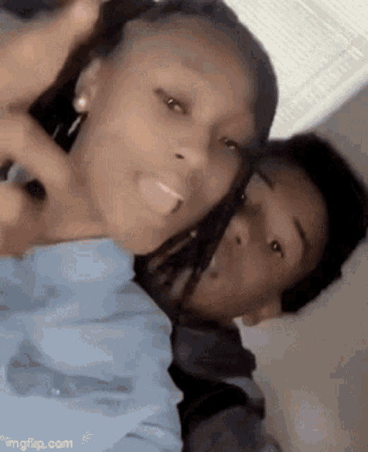 a boy and a girl are posing for a picture together . the girl is sticking her tongue out .
