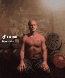 a man without a shirt is sitting on a bench with his hands on his knees and a tiktok sticker above him