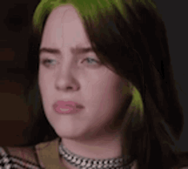 billie eilish is wearing a choker and has green hair .