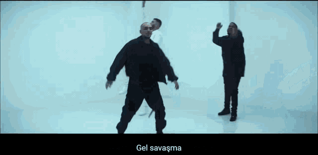 a man in a black jacket is dancing in a room with the words gel savaşma on the bottom