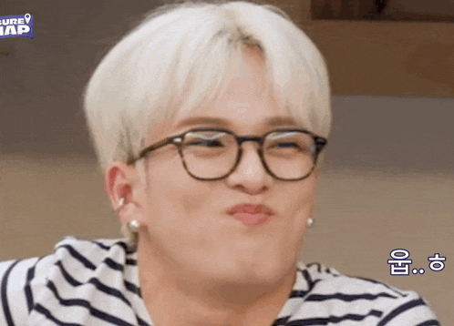 a close up of a person wearing glasses and a striped shirt making a funny face .