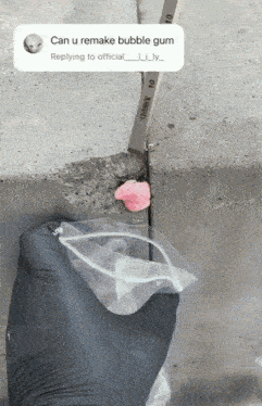 a person wearing black gloves is holding a bag of bubble gum in their hand