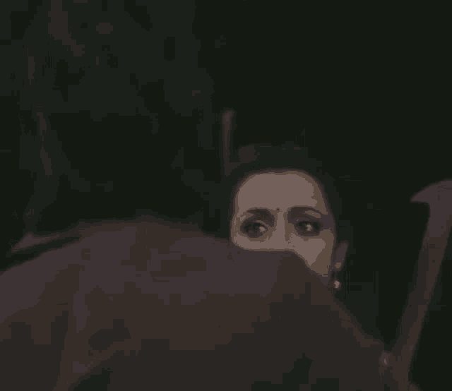 a woman with a nose ring is looking at a man 's face in a dark room .