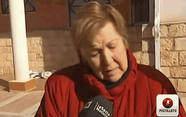 a woman wearing a red jacket is talking into a microphone that says " esxu noticias " on it