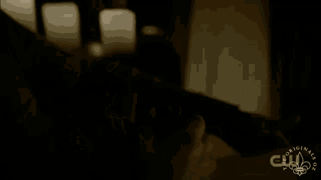 a blurry picture of a person sitting in a dark room with a cw logo in the background