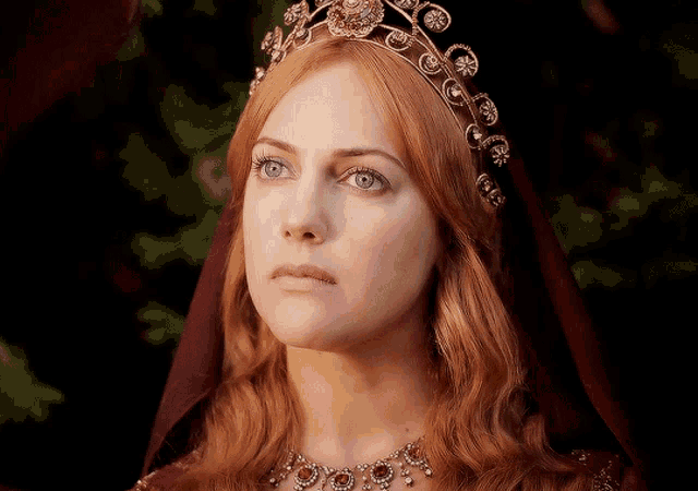 a woman with red hair is wearing a tiara and necklace