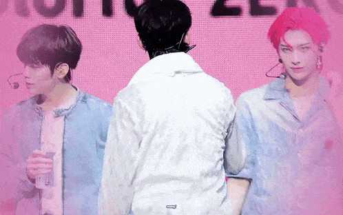 a man in a white jacket is standing in front of a pink background .
